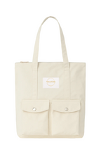 Beige tote bag with a small white label on a white background